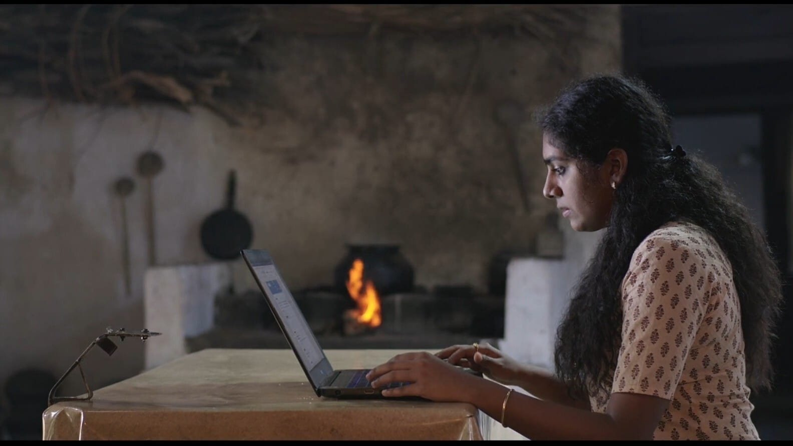 Girl in kitchen typing on laptop