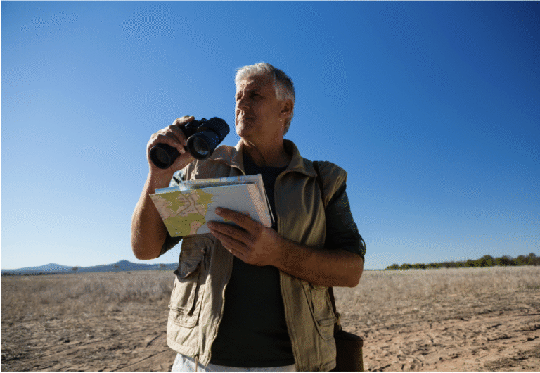Older man with map and binoculars searching for new path.
