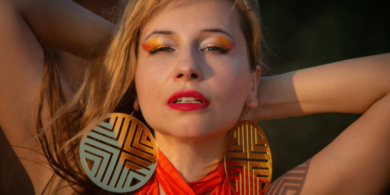 A blond lady with big earrings and makeup on, posing for a photograph