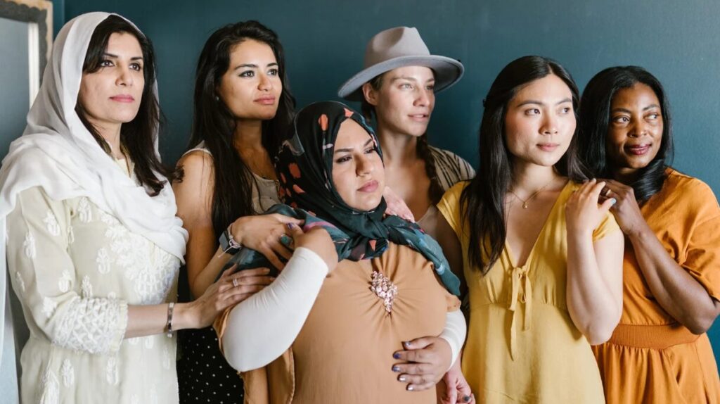 Diverse group of six women from different cultural and ethnic backgrounds standing together in solidarity.