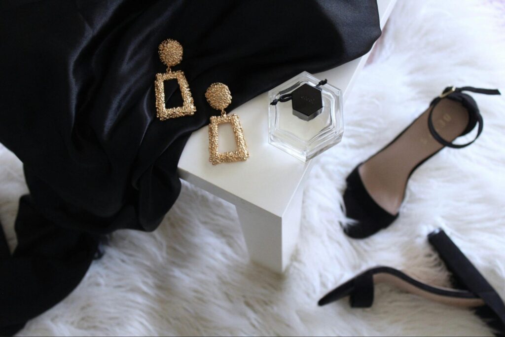 A flat lay photo of women's fashion accessories on a white table and a fluffy white rug.