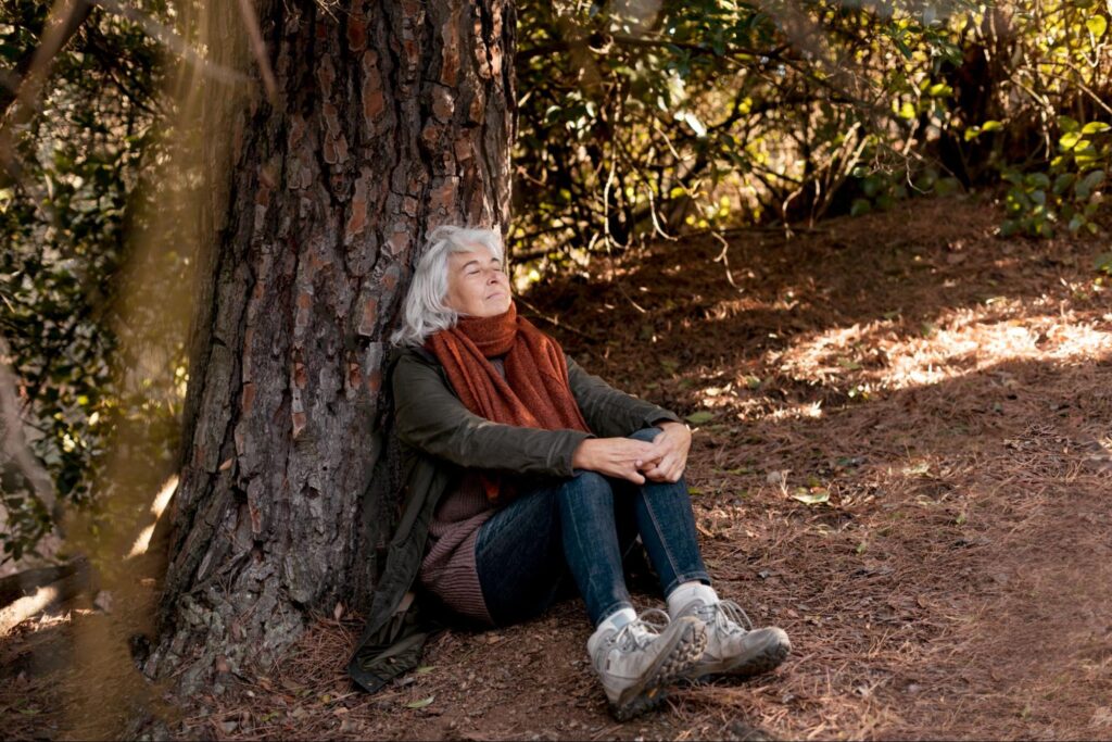 A person sitting calmly under a tree, eyes closed.