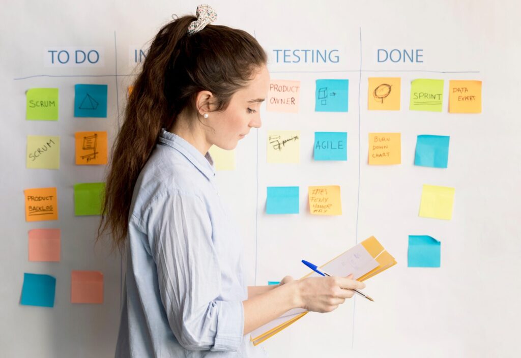 Focused woman writing on clipboard, organizing tasks with colorful sticky notes.