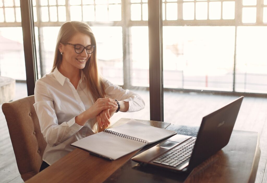 Smiling woman checks watch while working, representing productive and efficient work