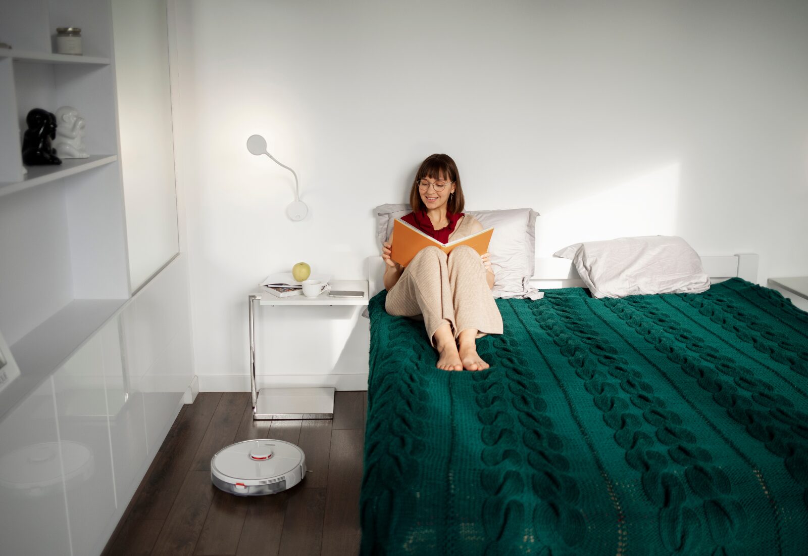 Woman reading peacefully in a minimalist, sunlit modern bedroom.