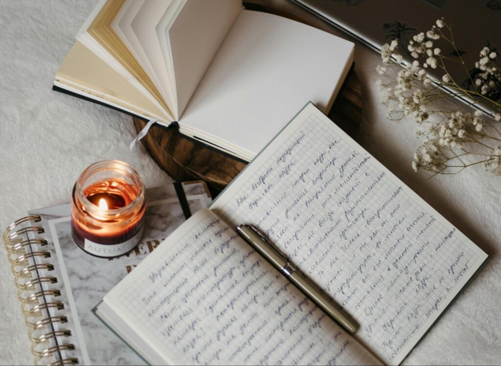 Alt text: a journal with a candle on a table.