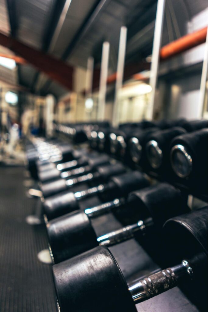 A rack of black dumbbells with chrome handles in a gym.
